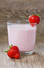 Milkshake with strawberry on a wooden rustic background