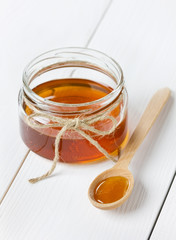 Honey in a wooden spoon and jar on a white background