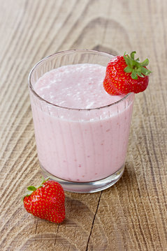 Milkshake with strawberry on a wooden rustic background