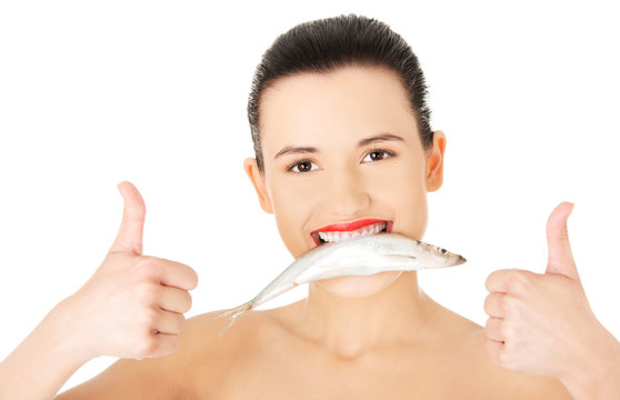 Fototapeta Portrait of happy nude woman with fish in mouth