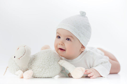 baby in white dress with a toy sheep