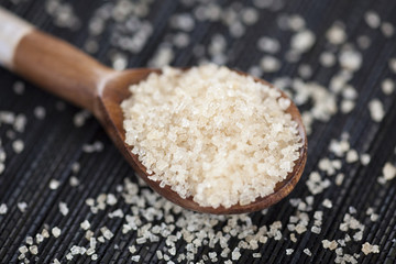 Brown cane sugar crystals in a wooden spoon
