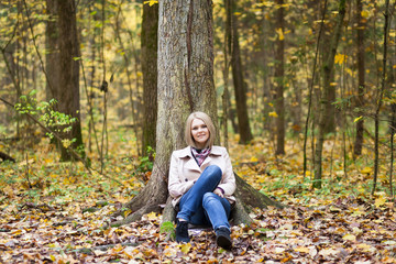 Blonde woman sitting under the tree in the forest