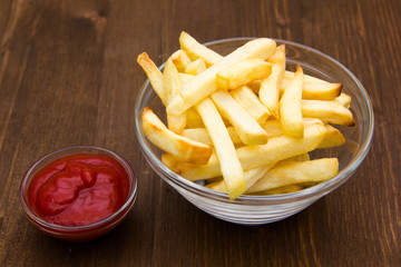 Bowl of chips and ketchup on wooden table