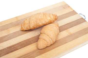 Fresh and tasty croissants on a cutting board isolated on white