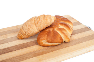Bun and tasty croissants on a cutting board isolated on white