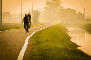 Elderly people in countryside bike road near little brook in fog