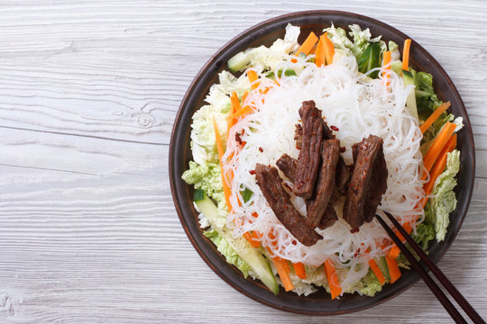 Chinese salad with rice noodles, meat and vegetables top view
