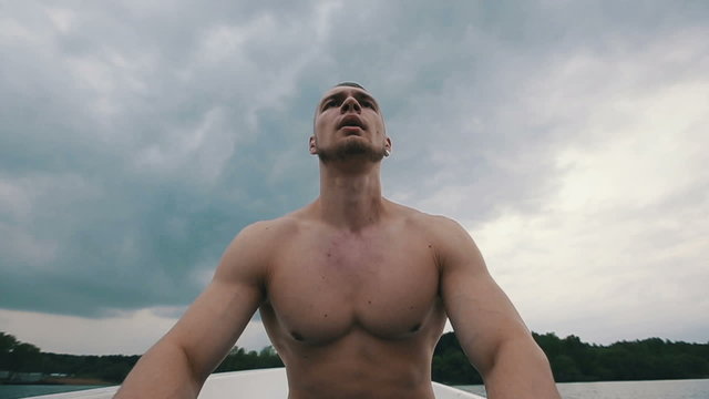 Muscular strong man row of boat floating with oars slow motion