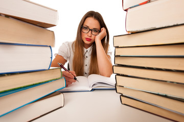 Stressed asian caucasian woman student learning in tons of books