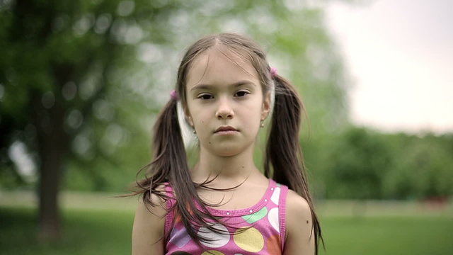 Portrait girl is angry in a summer park in slow motion