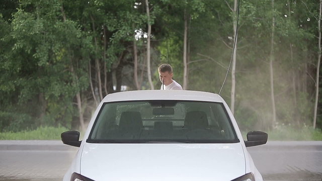 Man in a white t-shirt washes white car Slow motion