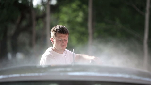 Man in a white t-shirt washes white car
