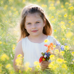 Cute little girl in a meadow with wild spring flowers