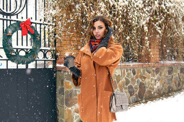 Woman with cup of coffee walk on snow street Christmas New Year