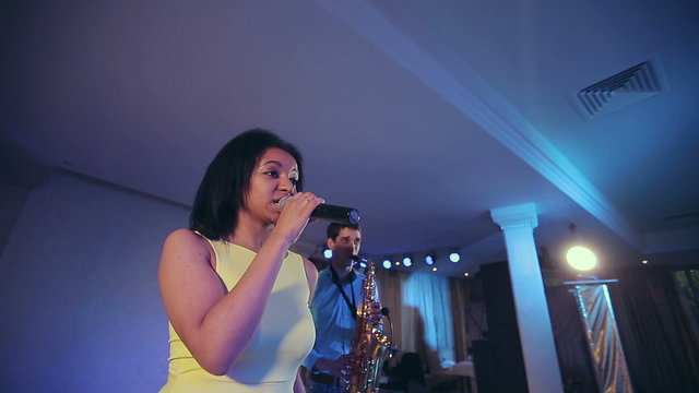 Black woman singer and her saxophone player performing on stage.