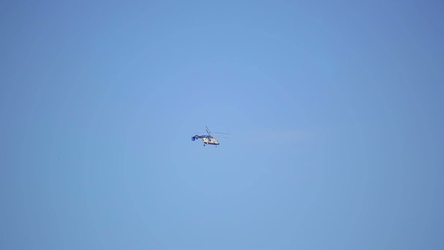 Small helicopter flies on blue sky background
