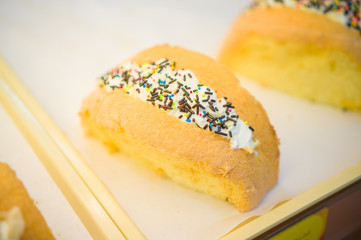 Bun bakery with filled cream, covered with chocolate and rainbow