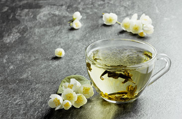 Fototapeta na wymiar cup of japanese green tea with jasmine flowers and lemon