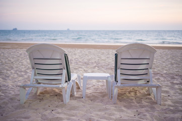 Fototapeta na wymiar Two beach chairs on sunset in evening