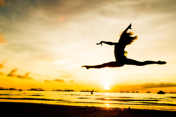 silhouette of jumping girl on tropical sunset sea and sky backgr