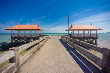 Long concrete pier on tropical beach with two canopy