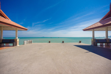 Long concrete pier on tropical beach with two canopy