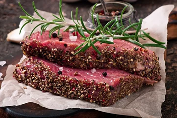 Photo sur Aluminium Steakhouse Raw beef steak with spices and a sprig of rosemary