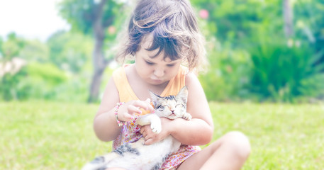 young child girl having fun with cat, little kitten on natural b