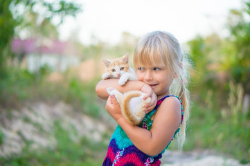 Obraz premium Adorable girl in color dress hold small kitten on hands