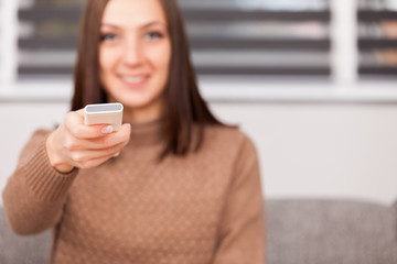 portrait of young smiling woman looking tv at home