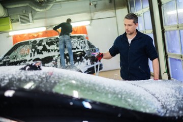 Man worker washing luxury car on a car wash