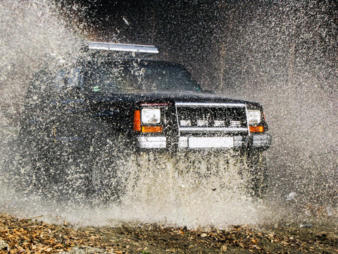jeep passes through the water creating large spray of water