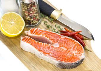 raw salmon steak with lemon and spices on a cutting board