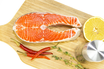 raw salmon steak with lemon and spices on a cutting board