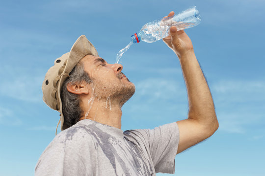 Man refreshing himself with water, outdoor shot.