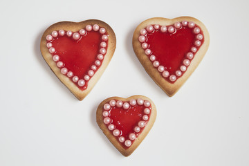 Three romantic heart shaped homemade Valentine cookies over a wh