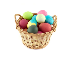 Fototapeta na wymiar Colorful Easter eggs inside straw wicker brown basket isolated