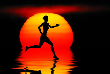 Woman jogging against a sunset ocean