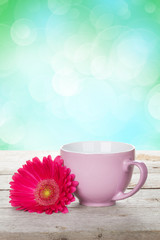 Cup of coffee and gerbera on wooden table