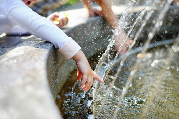 Closeup photo of child washing hands in a fountain - obrazy, fototapety, plakaty
