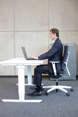 man in suit in correct sitting position at workstation