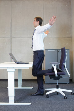 Business Man  Stretching In Standing Position At Desk