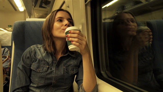 Young woman drinking coffee during train ride