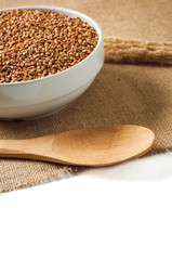 buckwheat and wooden spoon on burlap background. isolate