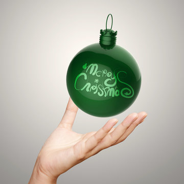 hand showing Merry Christmas in ornament ball