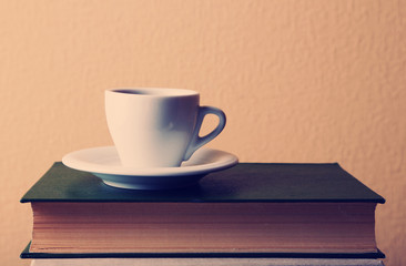 Old books and cup of coffee on table