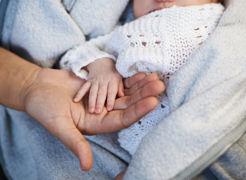 Mom keeps  miniature hand newborn baby in hands