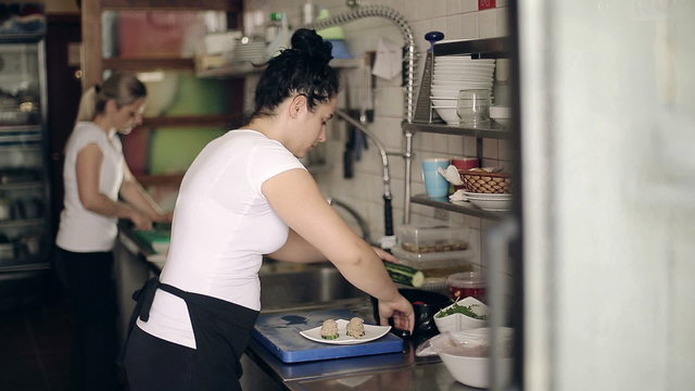 Restaurant kitchen woman preparing fish dishes for guests