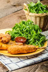 Corn dog with fresh arugula salad and hot dip